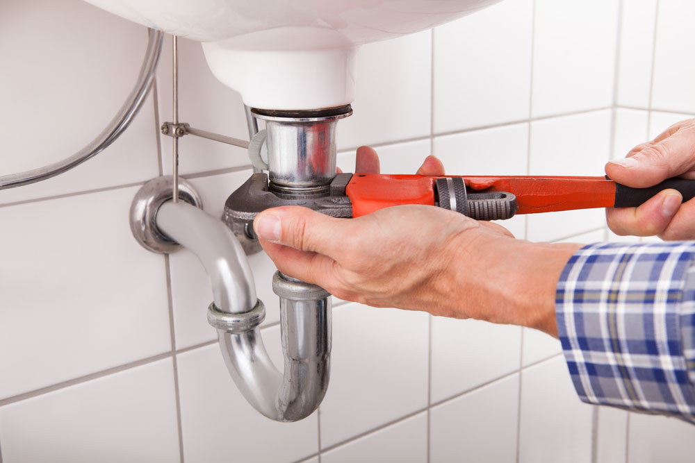 Plumber using a monkey wrench on a pipe line