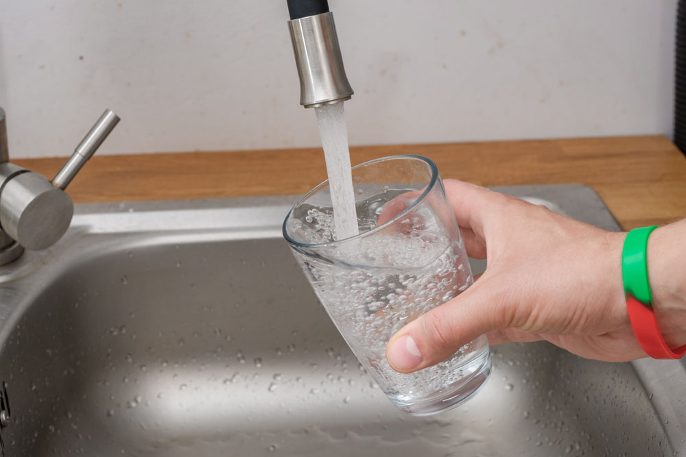 drinking glass being filled with water from the tap